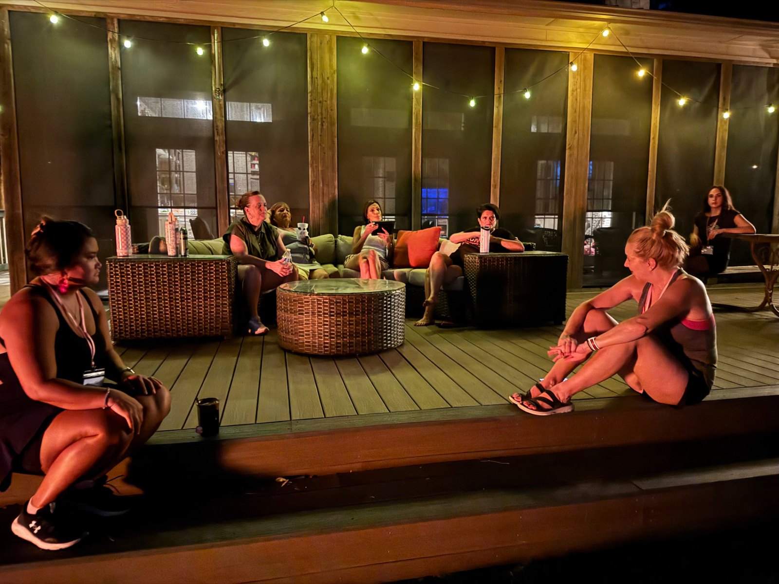 Women talking together on a string-lit porch at night