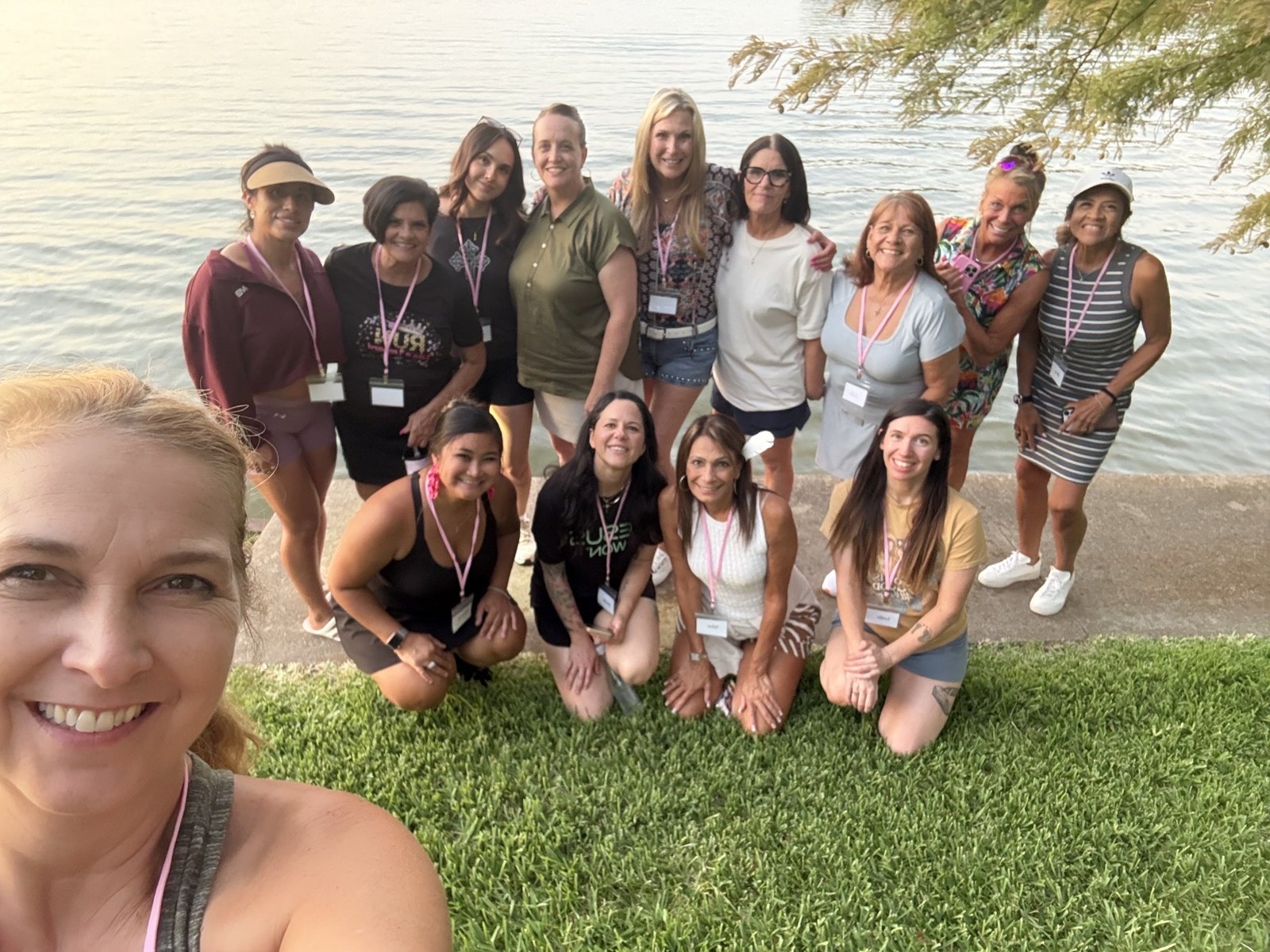 A joyful group photo of SHE Ventures women gathered by the water
