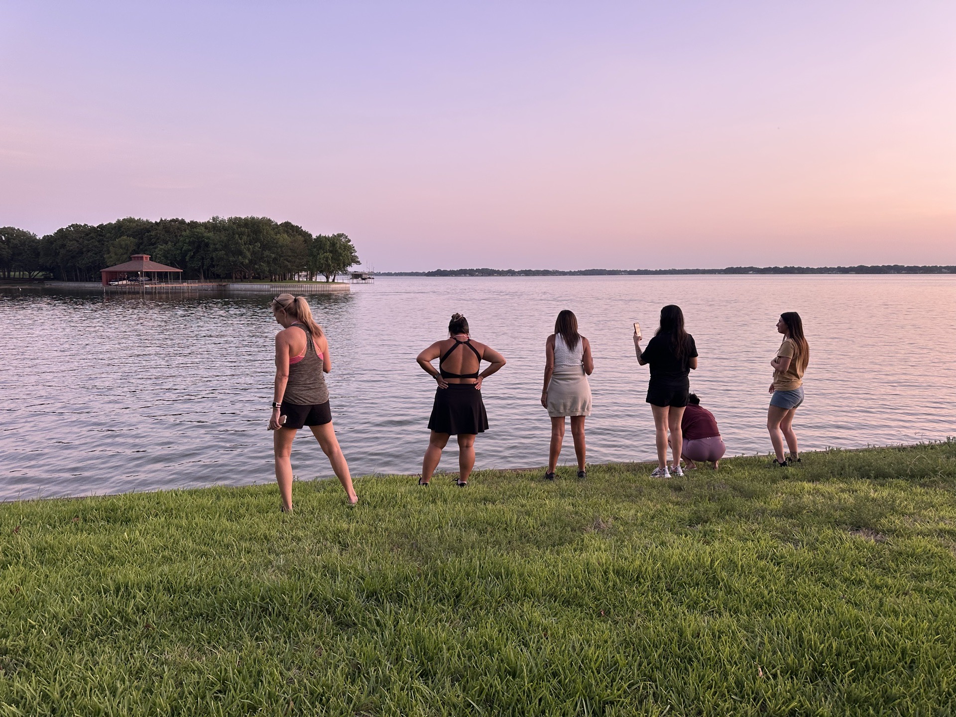SHE Ventures women gathered along the lakeshore watching a pastel sunset