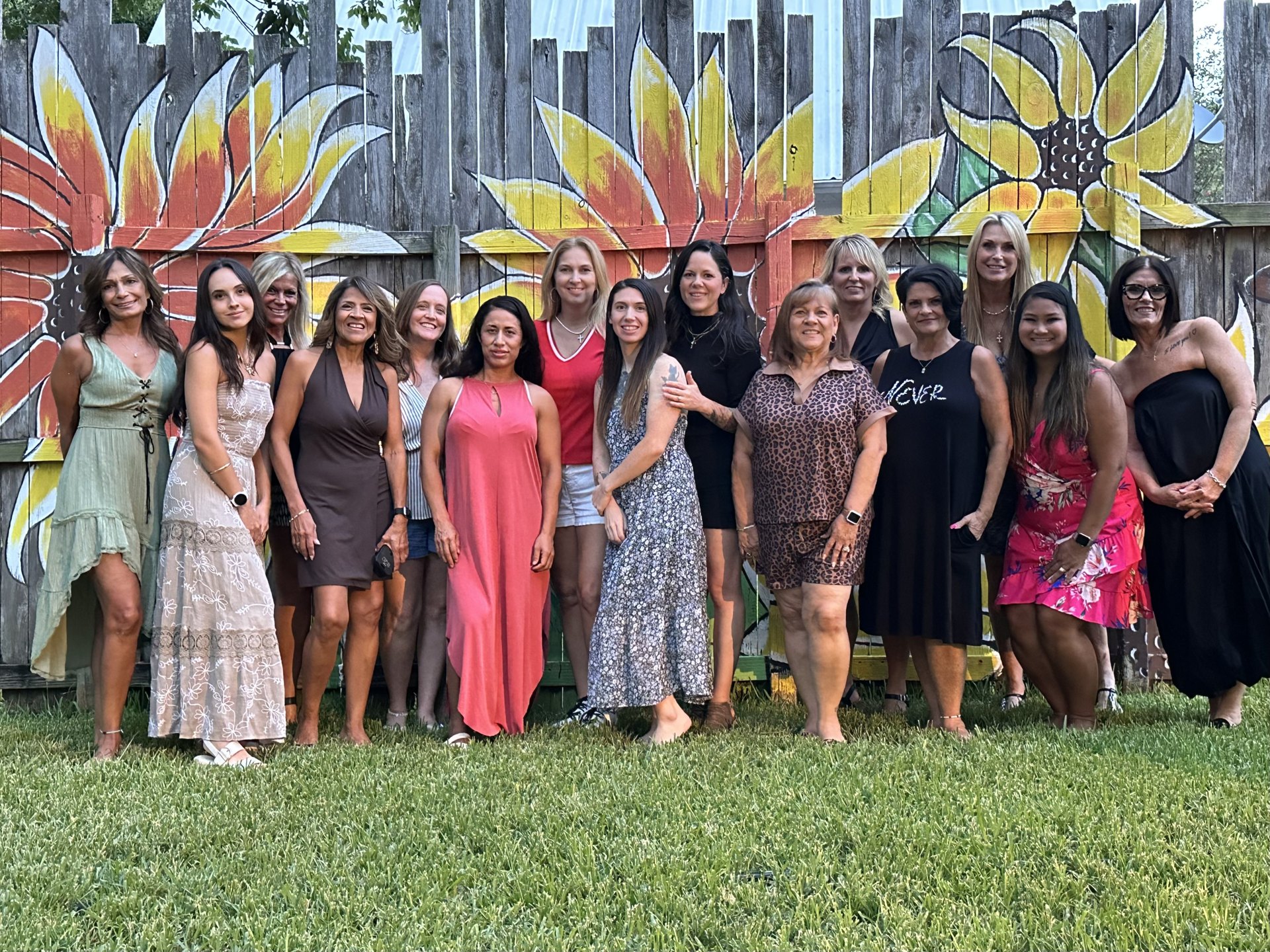 The SHE Ventures group standing together in front of a painted sunflower mural