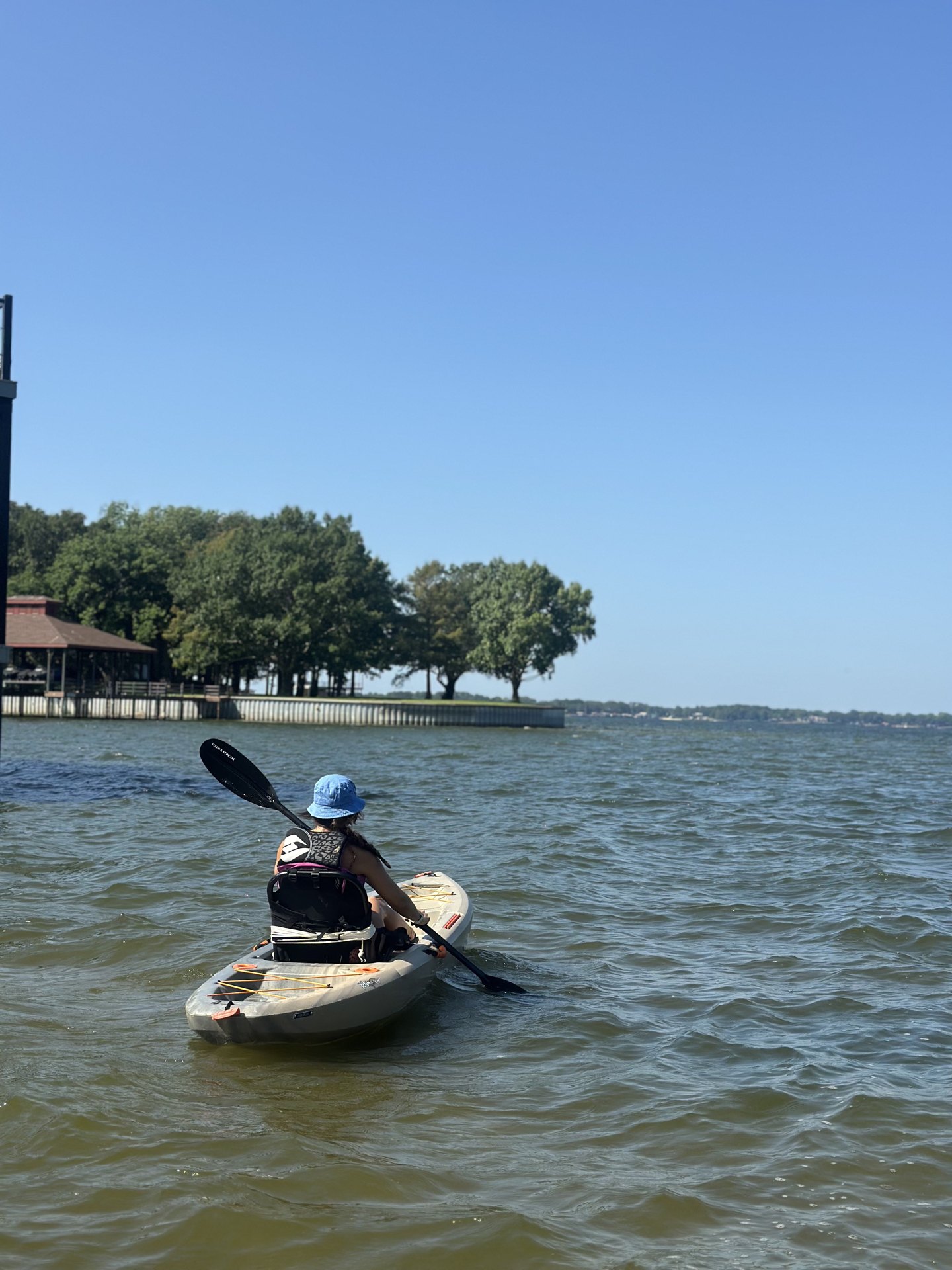 A woman kayaking out toward open water on a clear blue day